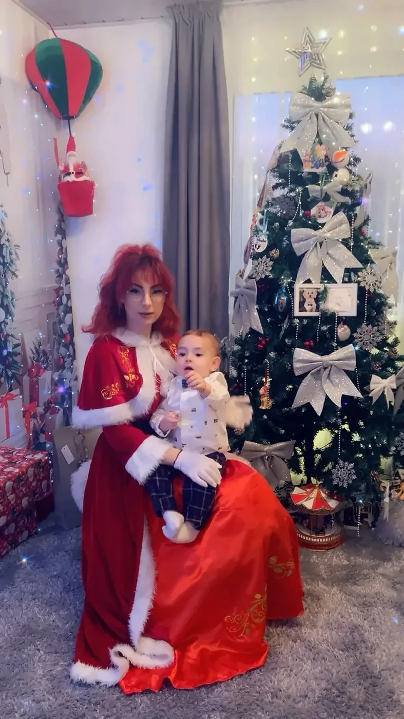 Doamna Crăciun alături de un copil într-un decor de Crăciun